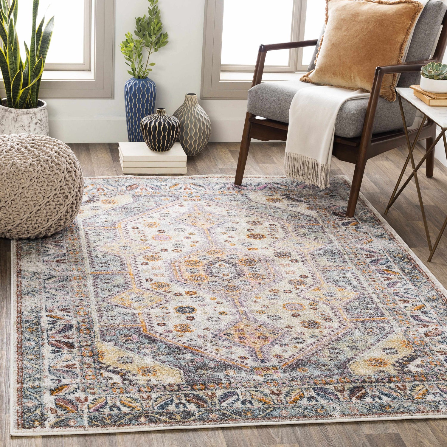 Living room scene with a Thornley Area Rug, gray chair, and natural light. The rug has blue, orange, and white tones. Roomscene-Rectangle