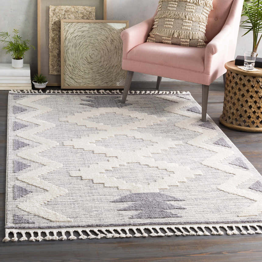 Styled room featuring the Thornburg rug. Gray, ivory rug with tassels, pink chair, and wood accents. Roomscene-Rectangle