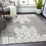 Living room scene with gray chair, pouf, and Thorntonville Outdoor Rug in black, gray, and white. Roomscene-Rectangle