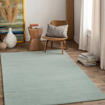 Living room scene with a Dusty Sage Brockton wool rug, wood chair, side table, and neutral decor. Roomscene-Rectangle