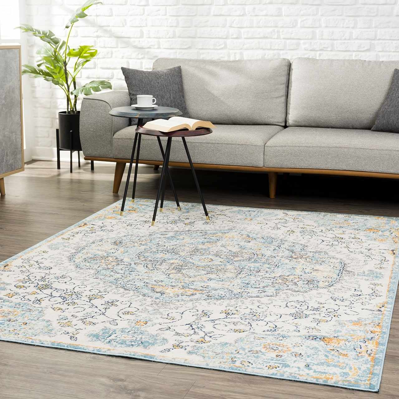 Living room scene with a gray sofa and Tigrit Blue 2301 Area Rug. The rug has blue, ivory, and turquoise colors. Roomscene-Rectangle
