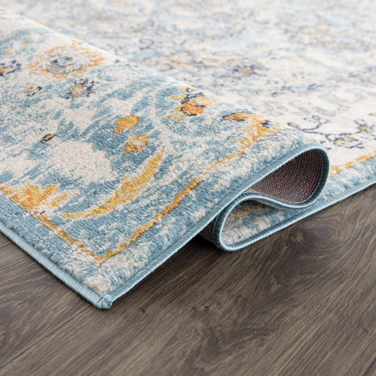 Close-up of the Tigrit Blue 2301 Area Rug showing its blue, ivory, and turquoise bohemian pattern and soft texture. Fold