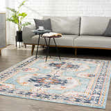 Living room scene with a Tigried Turquoise 2308 Area Rug, gray sofa, side tables, and a potted plant against a white brick wall. Roomscene-Rectangle