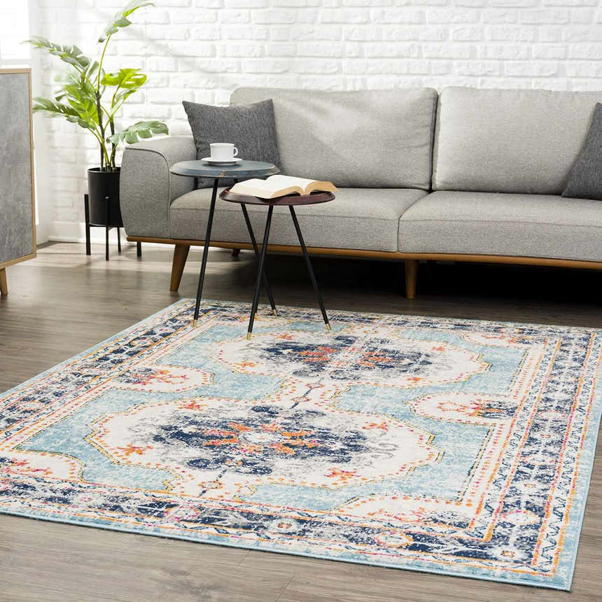 Living room scene with a Tigried Turquoise 2308 Area Rug, gray sofa, side tables, and a potted plant against a white brick wall. Roomscene-Rectangle