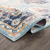 Close-up of Tigried Turquoise 2308 Area Rug showing its blue, ivory, and orange Bohemian-style pattern and soft texture. Fold
