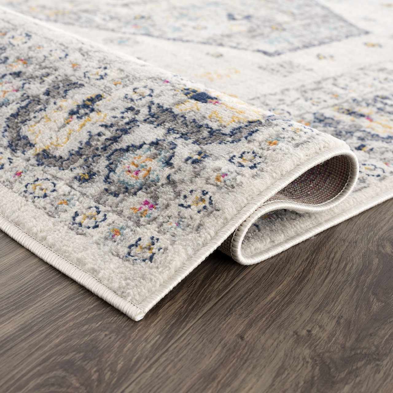 Close-up of Tigried Ivory 2309 Area Rug showing its ivory, blue, gray, pink, and yellow bohemian pattern and soft texture. Fold