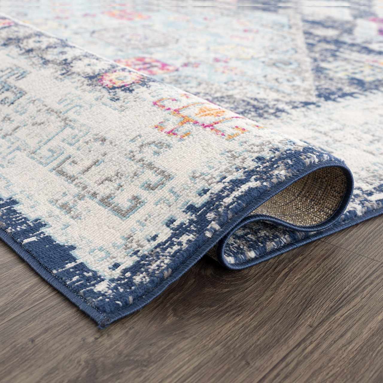 Close-up of the Tigriv Navy 2313 Area Rug showing its navy border and ivory, gray, pink, and orange bohemian pattern. Fold