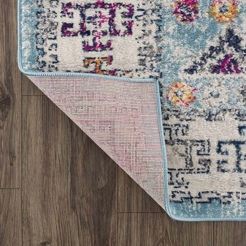 Close-up of the Tigris Turquoise 2314 rug showing its ivory, blue, pink, and orange bohemian pattern and machine-made backing. Fold