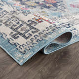 Close-up of the Tigris Turquoise 2314 Area Rug showing its ivory, blue, and orange bohemian pattern and soft texture. Fold