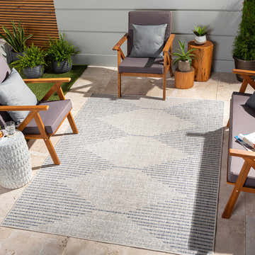 Patio scene with Stephan Gray & Blue Outdoor Rug, wood chairs, gray cushions, plants, and stone tile flooring. Roomscene-Rectangle