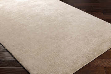 Close-up of Timpas Luxury Linen-Viscose Rug in dark red on dark wood floor. Soft, subtle texture. Hand-loomed rug. Corner