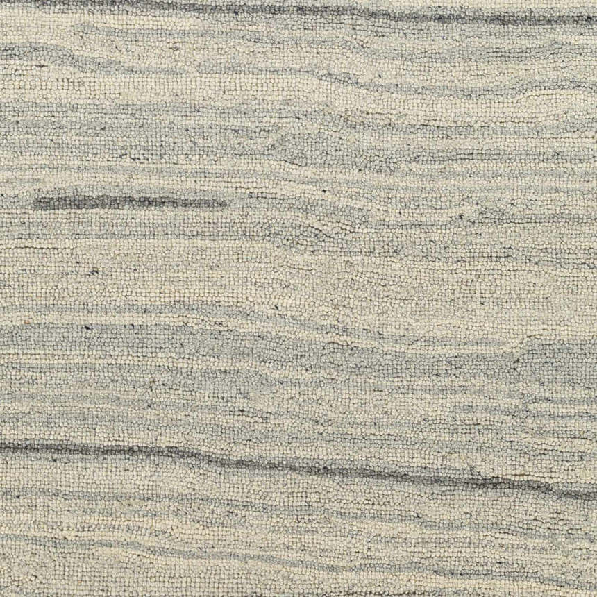 Close-up of the hand-tufted Tinubuan Area Rug. Light beige and gray wool rug with a subtle horizontal stripe pattern. Swatch