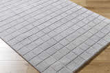 Close-up of the hand-tufted Toshi Sterling Gray Area Rug, a contemporary wool rug with a geometric square pattern. Corner
