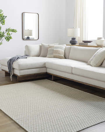 Living room scene with a light silver Tevah Wool Rug, white sectional sofa, wood floors, and a neutral color palette. Roomscene-Rectangle