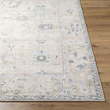 Close-up of the beige and charcoal Toddy Area Rug showing its traditional pattern and texture on wood floor. Front