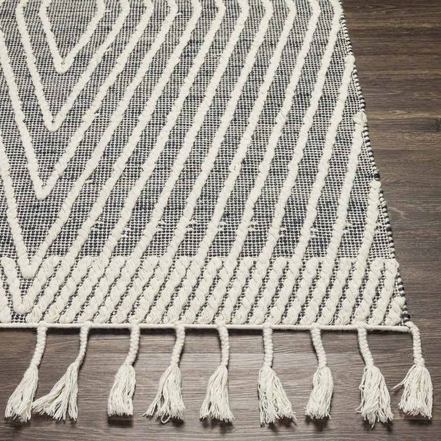 Close-up of the Tamayong Tasseled Jute&Wool Rug showing its black, cream, and ink blue geometric pattern and tasseled edge. Front