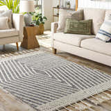 Living room scene with a Tamayong Tasseled Jute & Wool Rug in black and cream, styled with a sofa and chairs. Roomscene-Rectangle