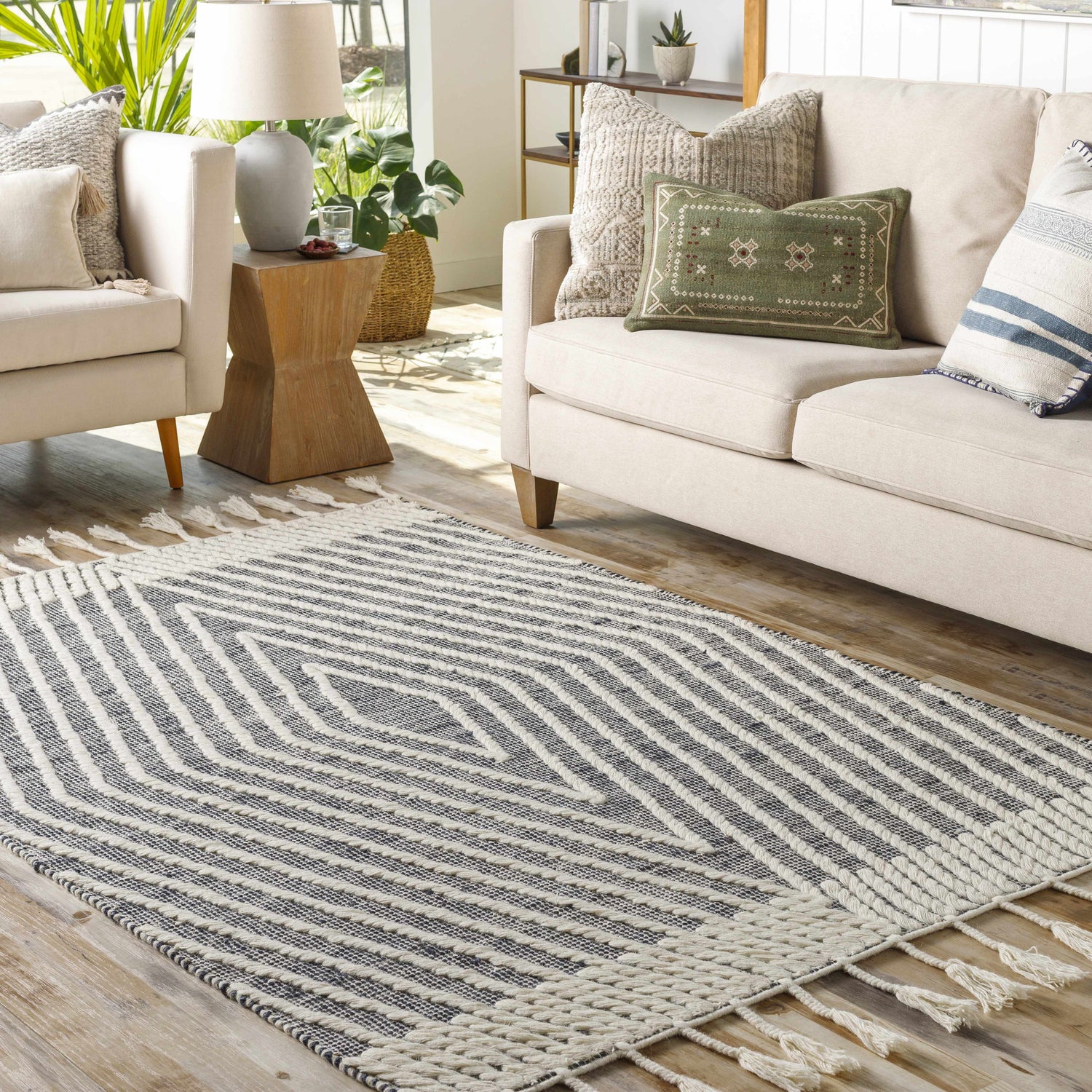 Living room scene with a Tamayong Tasseled Jute & Wool Rug in black and cream, styled with a sofa and chairs. Roomscene-Rectangle