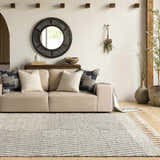Living room scene with a beige sofa and the Tamayong Tasseled Jute&Wool Rug in black and cream, creating a bohemian farmhouse vibe. Roomscene-Rectangle