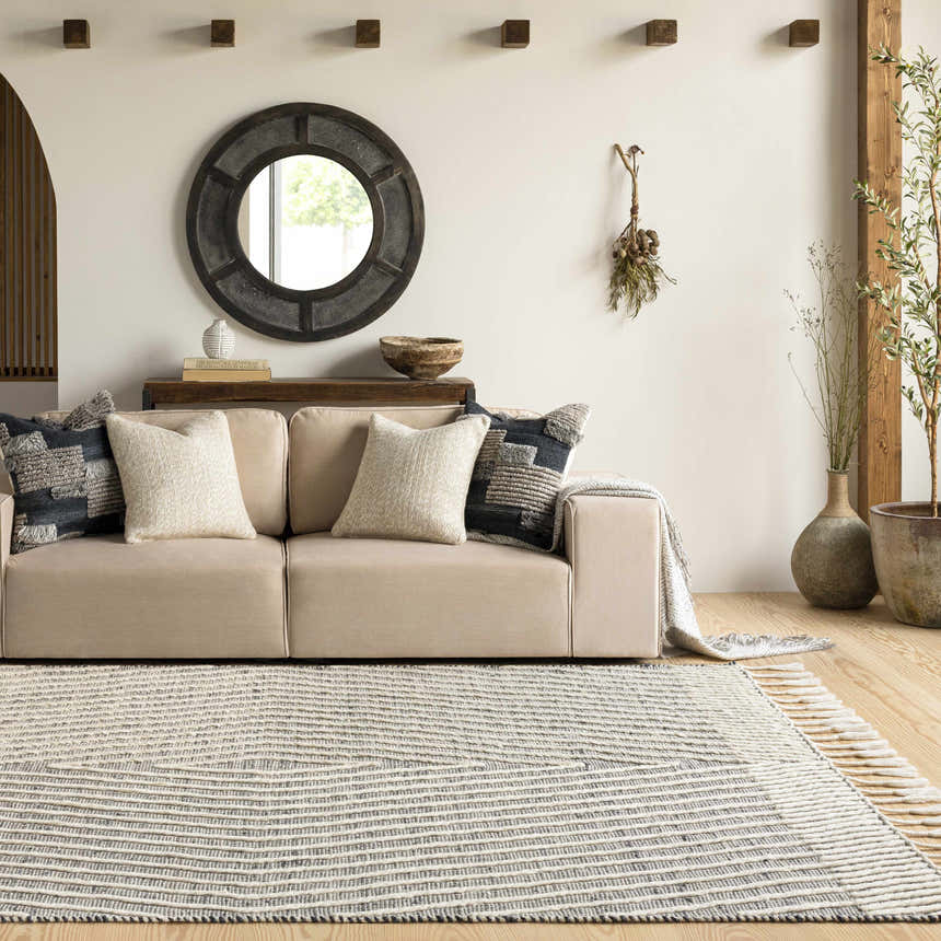 Living room scene with a beige sofa and the Tamayong Tasseled Jute&Wool Rug in black and cream, creating a bohemian farmhouse vibe. Roomscene-Rectangle