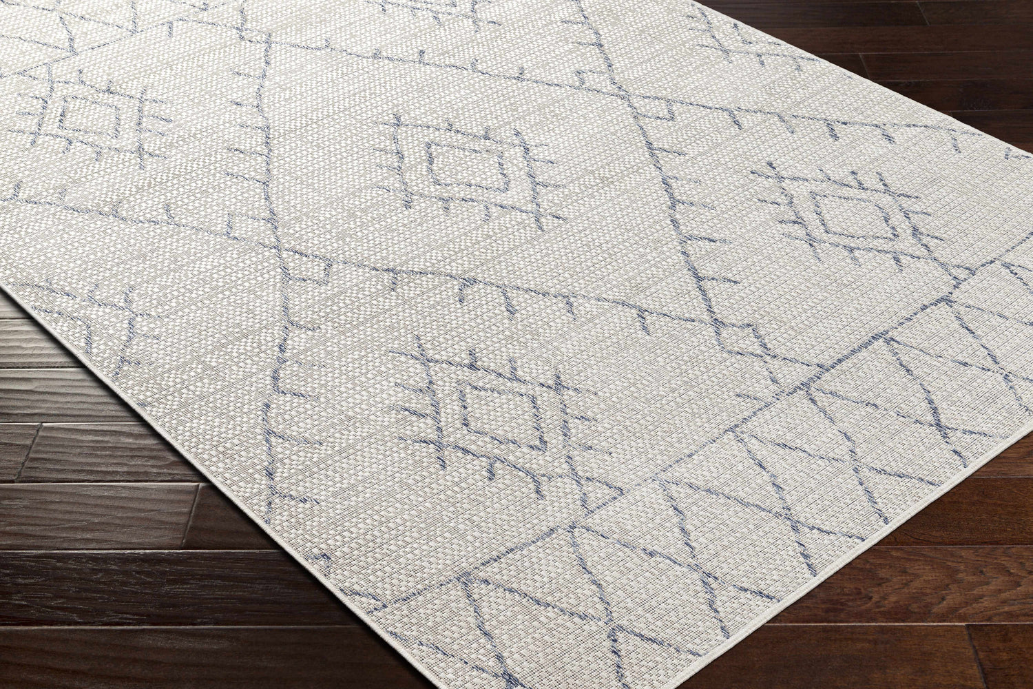 Close-up of Marwood Gray&Blue Nordic Rug showing geometric pattern, woven texture, and blue accents on dark wood floor. Corner
