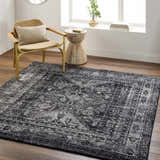 Farmhouse living room scene with a black and gray Toni Area Rug, woven chair, and wood side table. Roomscene-Rectangle