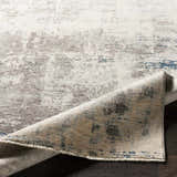 Close-up of the Tonalea Carved Statement Area Rug showing its ivory, gray, and blue abstract pattern and carved texture. Fold