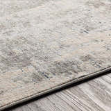 Close-up of the Tonalea Carved Statement Area Rug showing its subtle blue, gray, and ivory tones and carved texture on wood floor. Texture