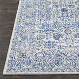 Close-up of the Truxton Area Rug. Light beige rug with a distressed navy, vintage-inspired pattern. Front