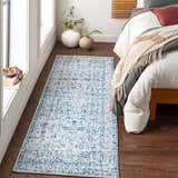 Bedroom scene with a blue and beige Truxton Area Rug runner next to a bed with neutral bedding. Roomscene-Runner