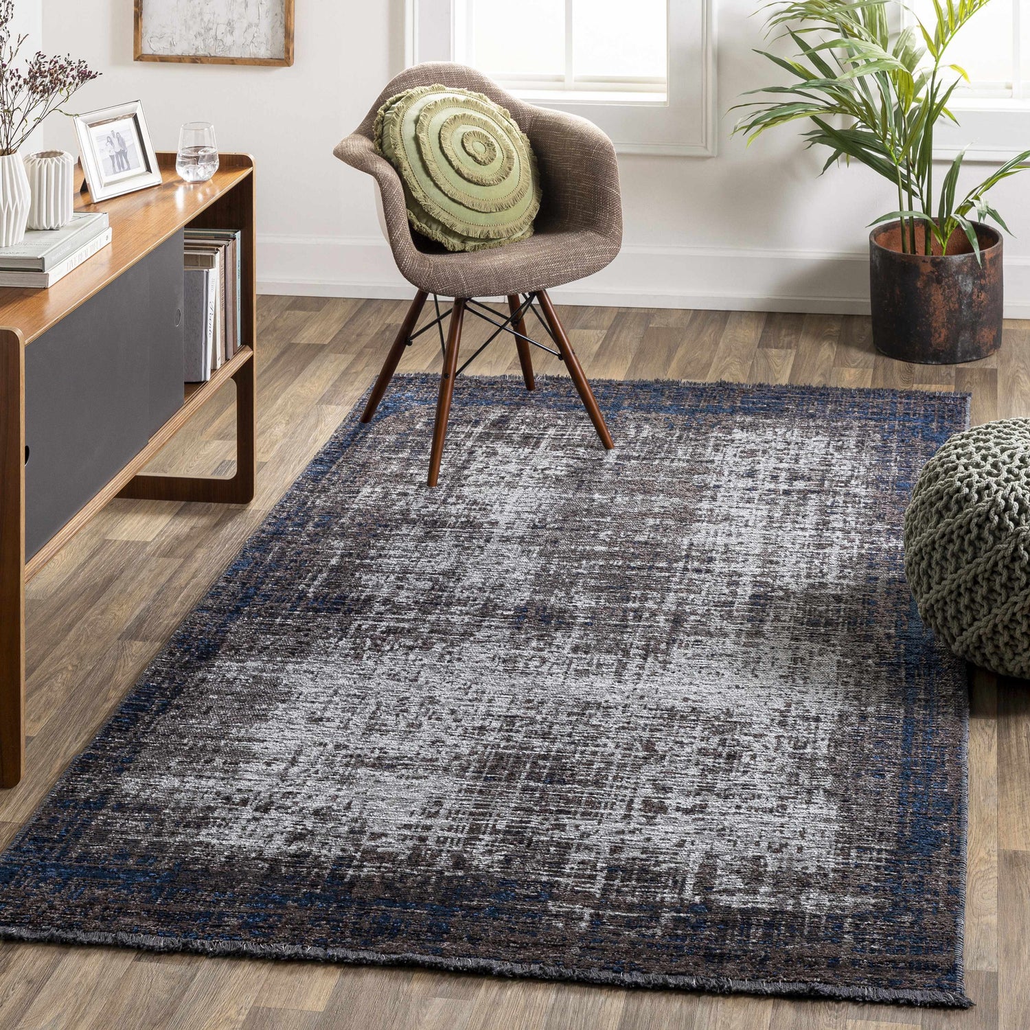 Living room scene with a Binh Black Area Rug, wood floors, chair, cabinet, and potted plant. Roomscene-Rectangle