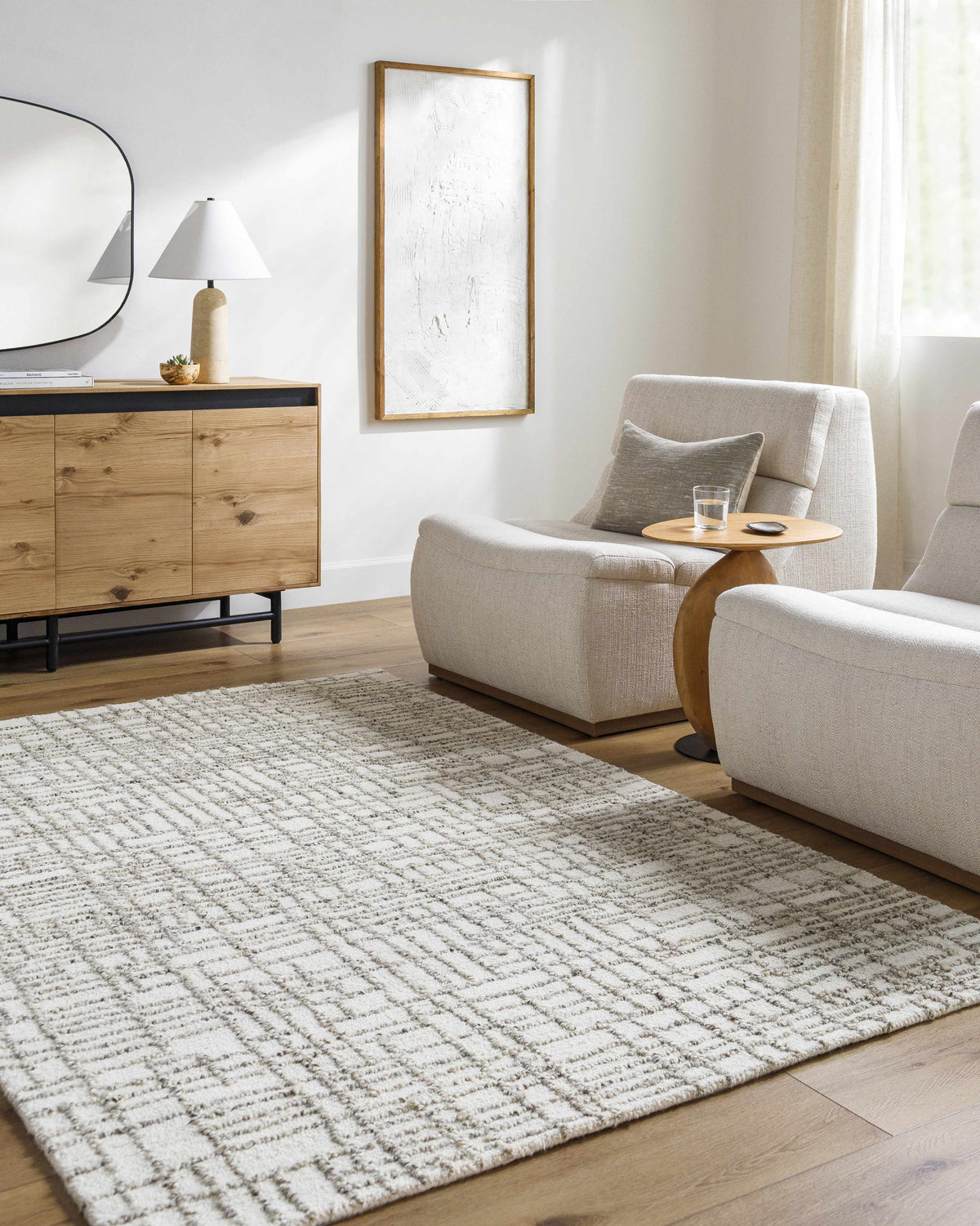 Living room scene with light silver Tibby Area Rug, neutral chairs, wood cabinet, and minimalist decor. Roomscene-Rectangle