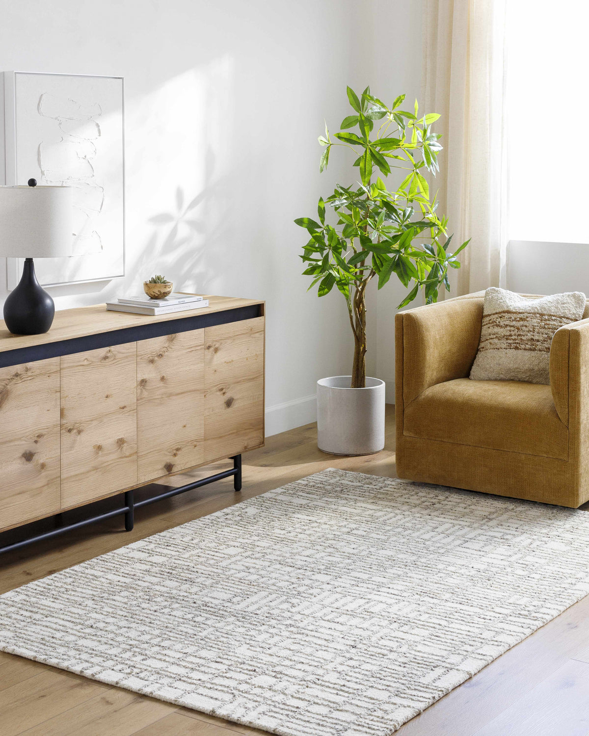 Living room scene with a light silver Tibby Area Rug, wood cabinet, and mustard-colored chair. Roomscene-Rectangle