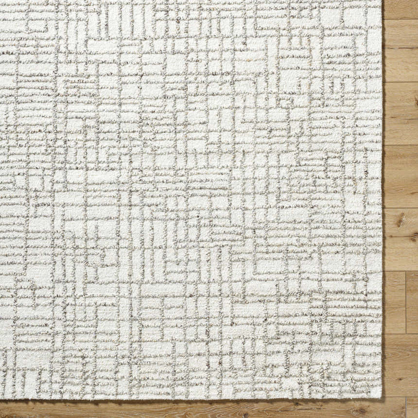 Close up of the hand tufted Tibby Area Rug. Light silver wool rug with a silver gray geometric pattern. Corner