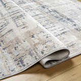 Close-up of the Tut Textured Luxe Rug showing its charcoal, ivory, beige, and gray contemporary design and soft texture. Fold