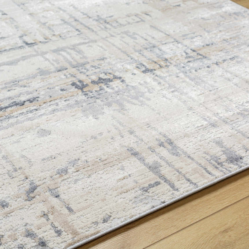 Close-up of the textured Tut Luxe Rug in charcoal, ivory, light beige, and gray on a wood floor. Texture