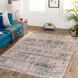 Living room scene with a blue sofa and the Tut Textured Luxe Rug in charcoal, ivory, and beige tones. Roomscene-Rectangle
