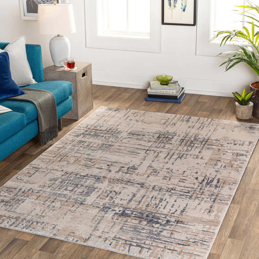 Living room scene with a blue sofa and the Tut Textured Luxe Rug in charcoal, ivory, and beige tones. Roomscene-Rectangle