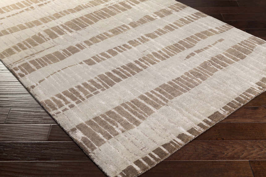 Close-up of the Turbeville Premium Area Carpet. Dark brown and light beige stripes on a hand-knotted wool rug. Corner