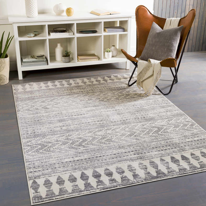Living room scene with gray Tuy Area Rug, leather chair, white console table, and gray wood floors. Roomscene-Rectangle