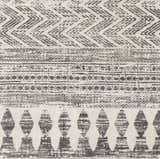 Close-up of the Tuy Area Rug featuring a gray bohemian-inspired geometric pattern and textured weave. Swatch