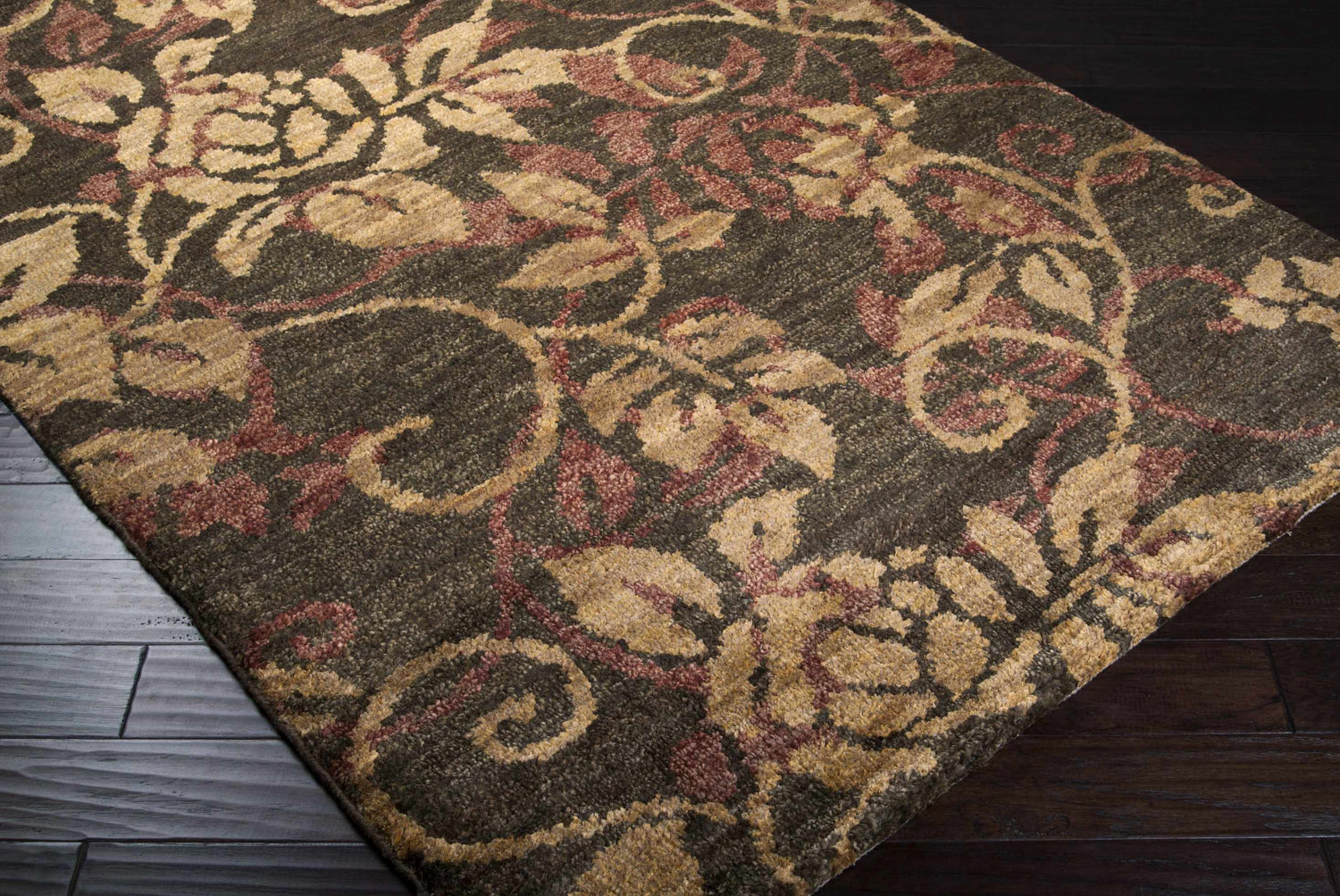 Close-up of the Uhland Jute Carpet. Hand-knotted rug with brick red, dark brown, and medium brown floral pattern. Natural fibers. Corner