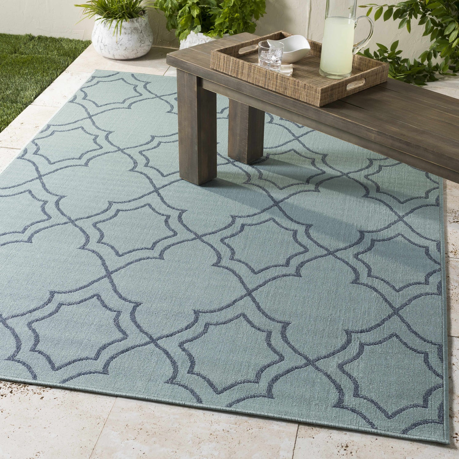 Outdoor patio scene with pale blue Ursa Area Rug, navy geometric pattern, and wood bench with lemonade. Roomscene-Rectangle
