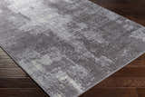 Close-up of the contemporary Victorias Area Rug. Charcoal, cream, light gray, and taupe abstract pattern. Corner