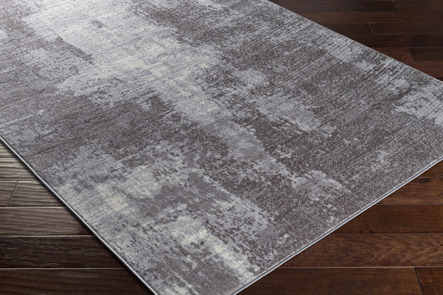 Close-up of the contemporary Victorias Area Rug. Charcoal, cream, light gray, and taupe abstract pattern. Corner