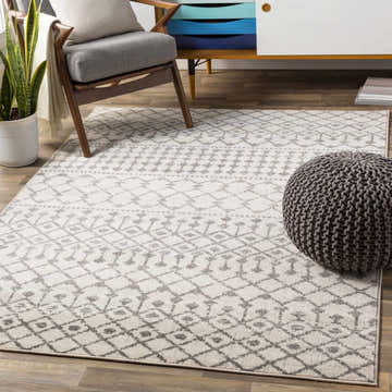 Living room scene with a gray chair, pouf, and the Vicksburg All Over Pattern Rug in charcoal, gray, and light beige. Roomscene-Rectangle