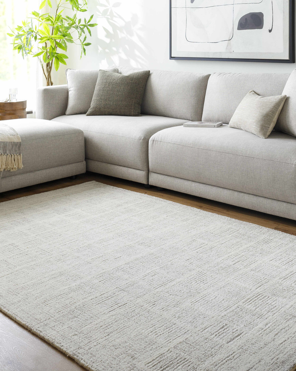Living room scene with a light silver Urian Area Rug, gray sectional, and modern art. Roomscene-Rectangle