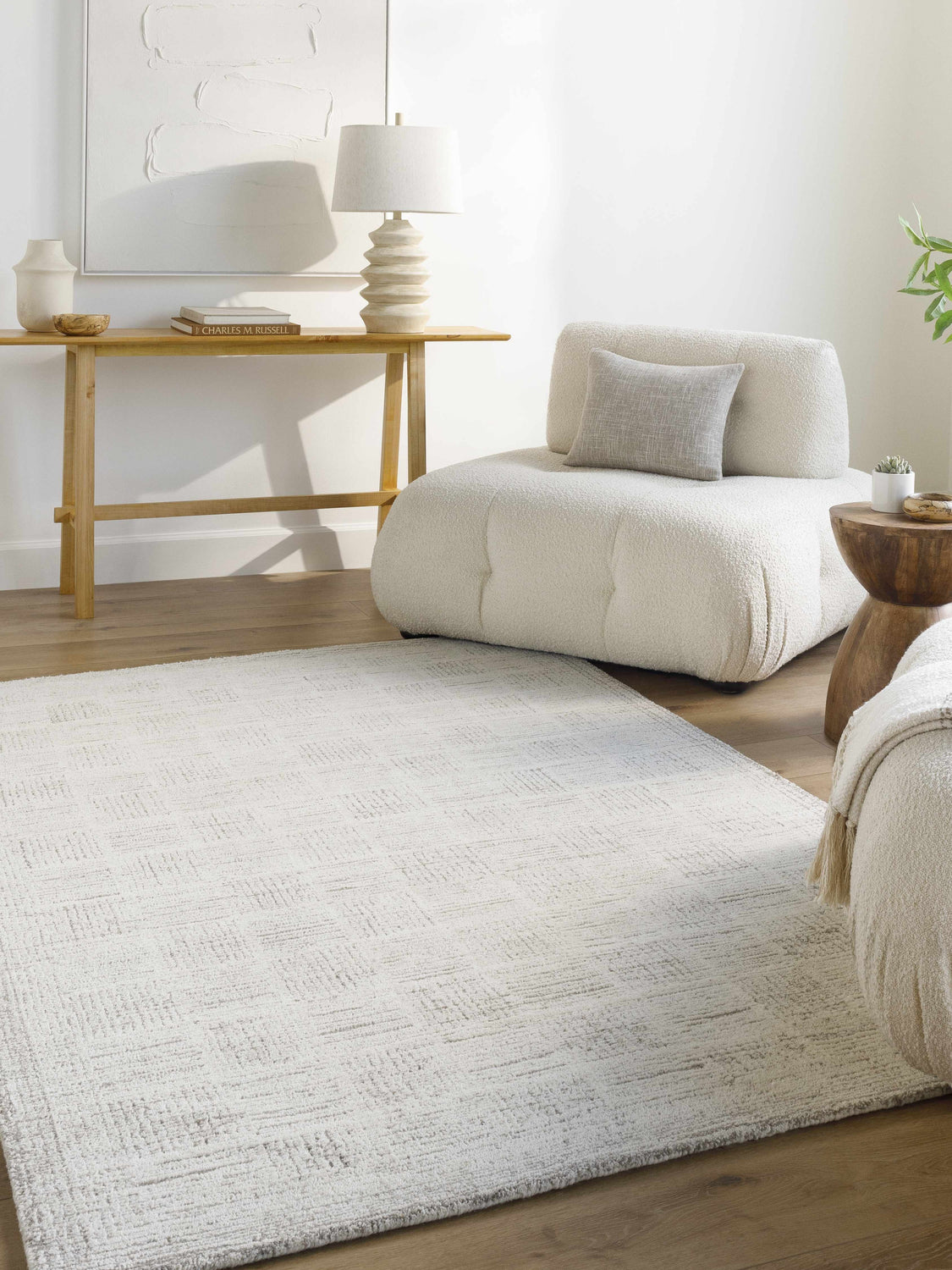 Living room scene with a light silver Urian Area Rug, a cream boucle chair, and a light wood console table. Roomscene-Rectangle