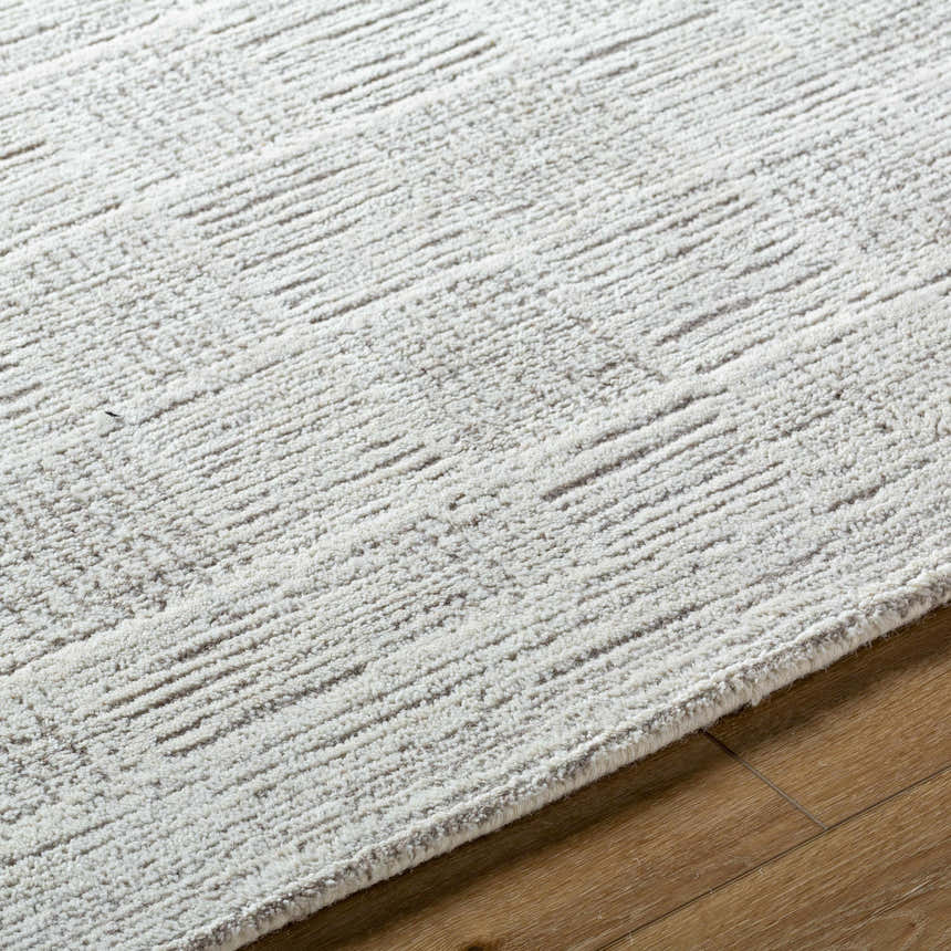 Close-up of the Urian Area Rug. Light silver wool rug with a subtle, contemporary striped pattern and soft, textured pile. Texture