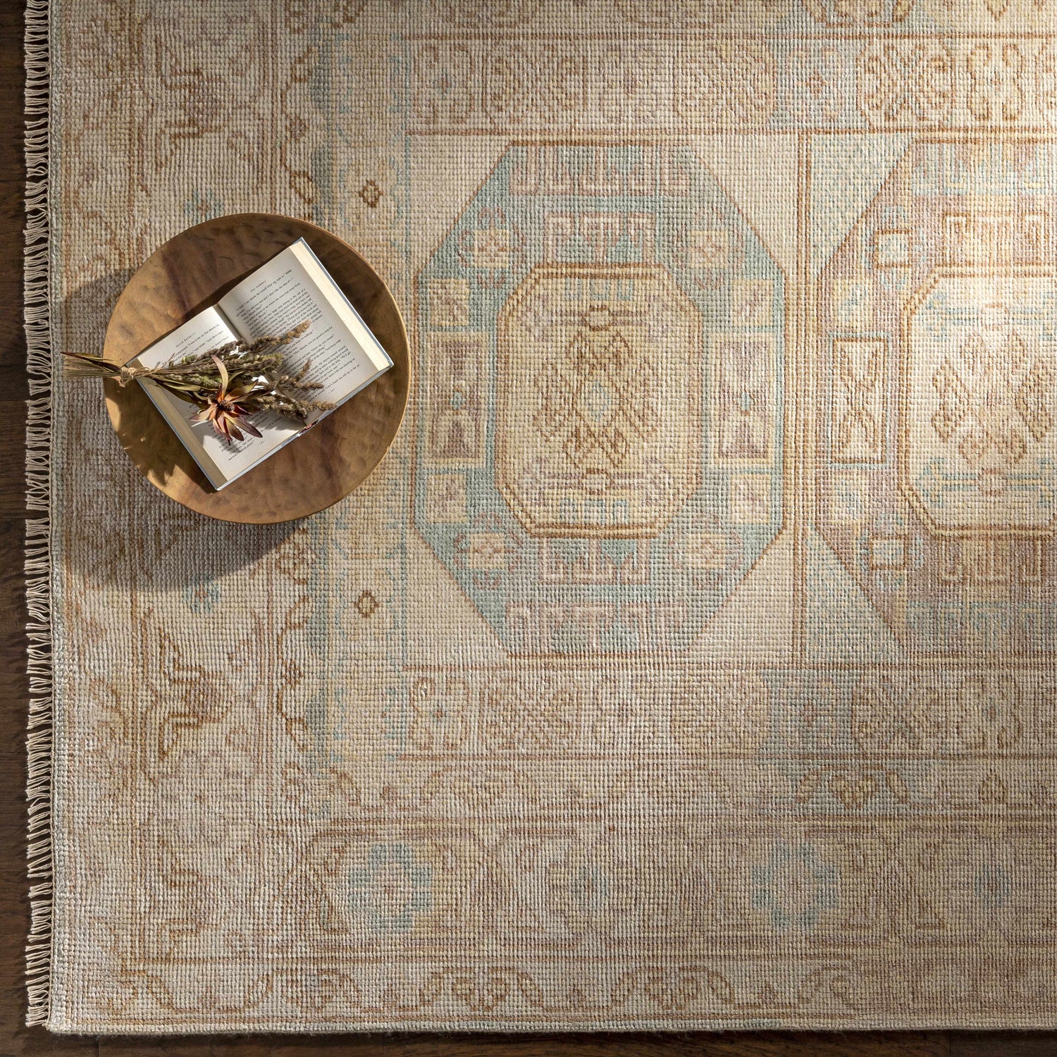 Close-up of the hand-knotted Villareal Area Rug in cream, dusty pink, ice blue, and beige with a traditional Oriental pattern. Styleshot